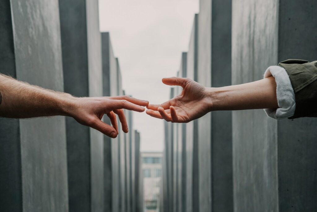 Two hands reaching towards each other, surrounded by gray concrete structures, photo.