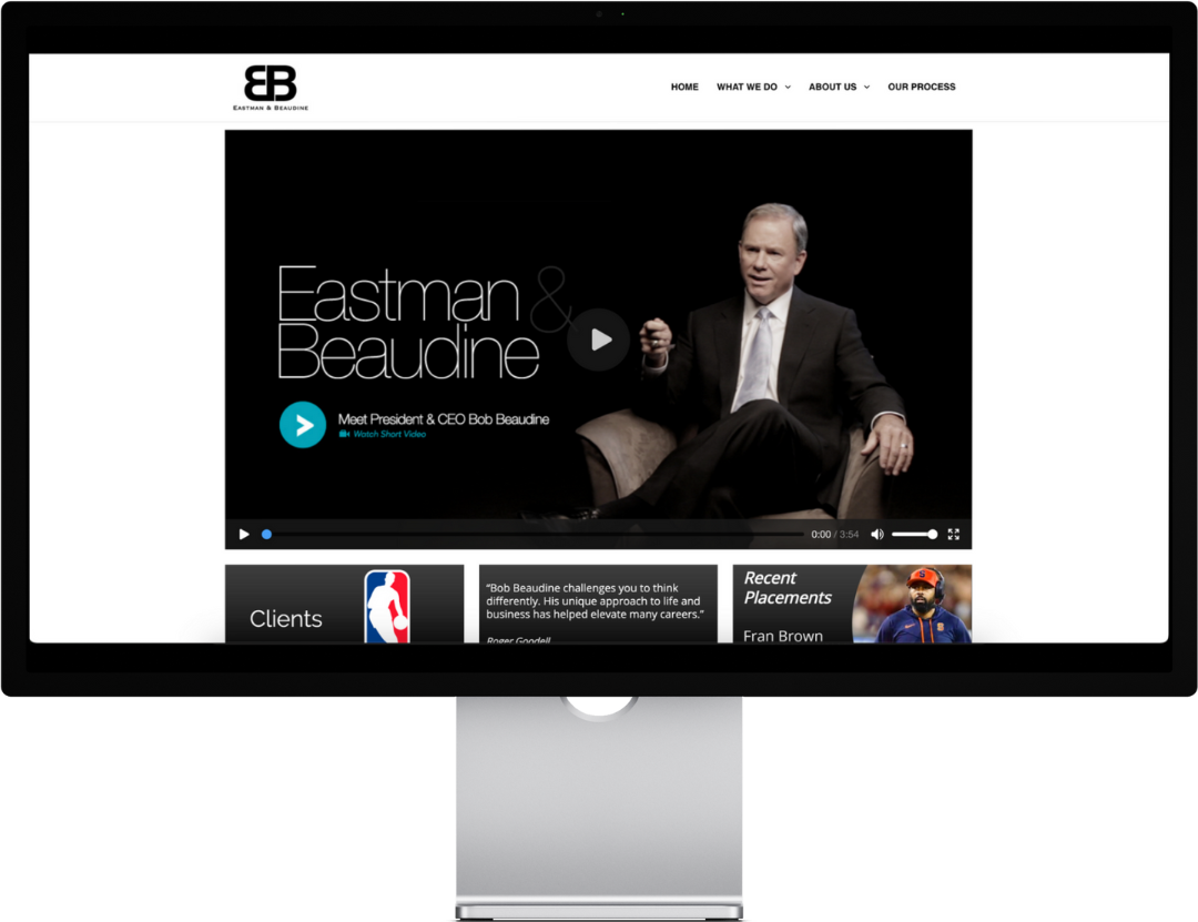 Man in suit speaking on video, "Eastman & Beaudine" text, website screenshot.